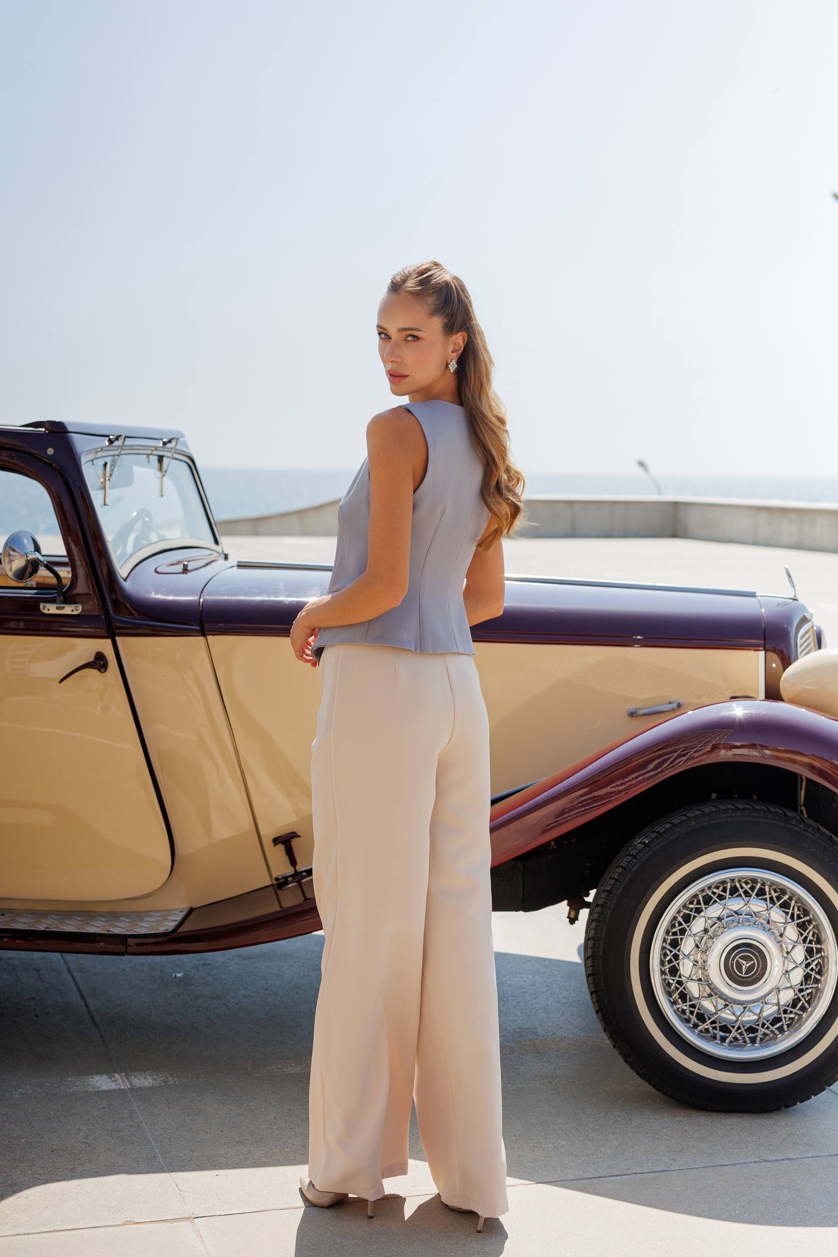Woman standing next to a vintage car on a sunny day