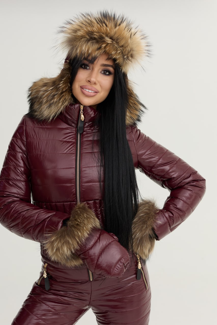 Person wearing a maroon puffer jacket with fur trim on a white background