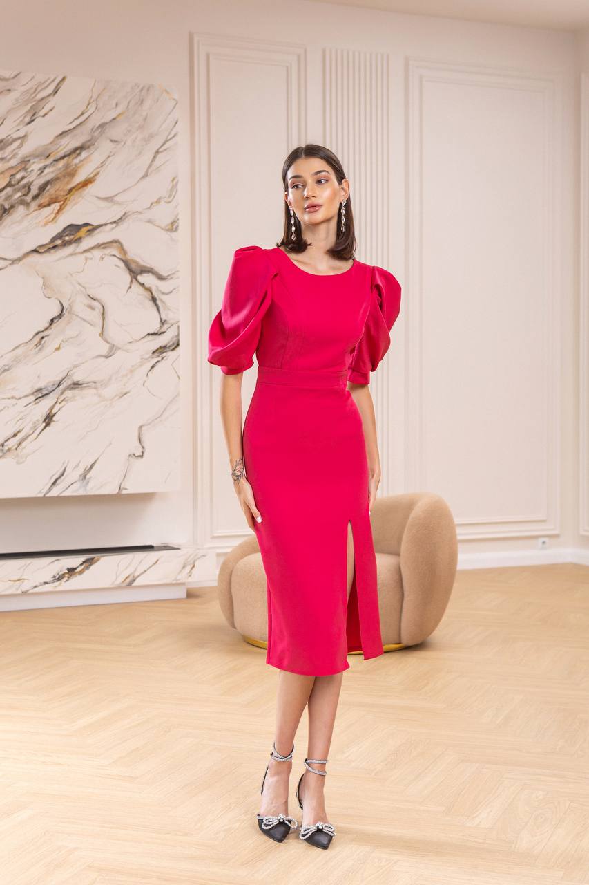 Woman in a bright pink dress standing in an elegant room with marble wall.