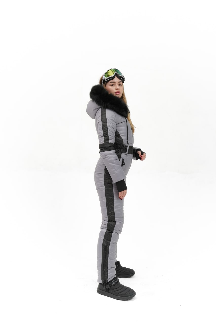 Person wearing a gray and black ski suit with goggles on a white background