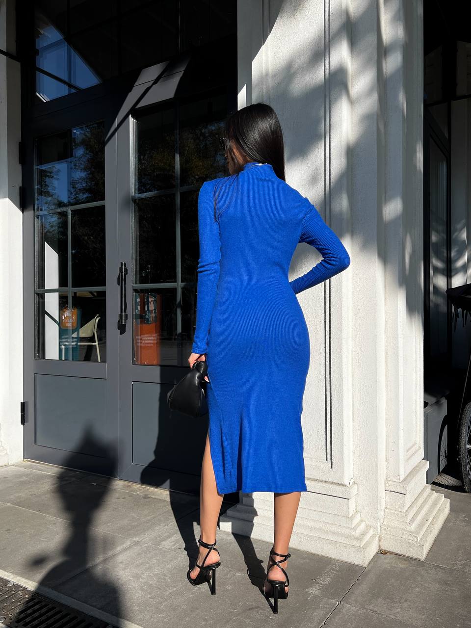 Woman in a blue dress standing outside a building