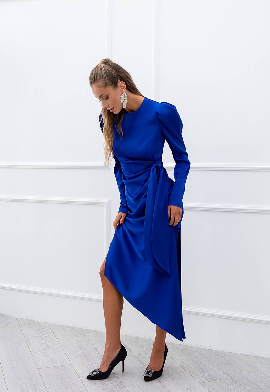 Woman wearing a blue dress against a white wall