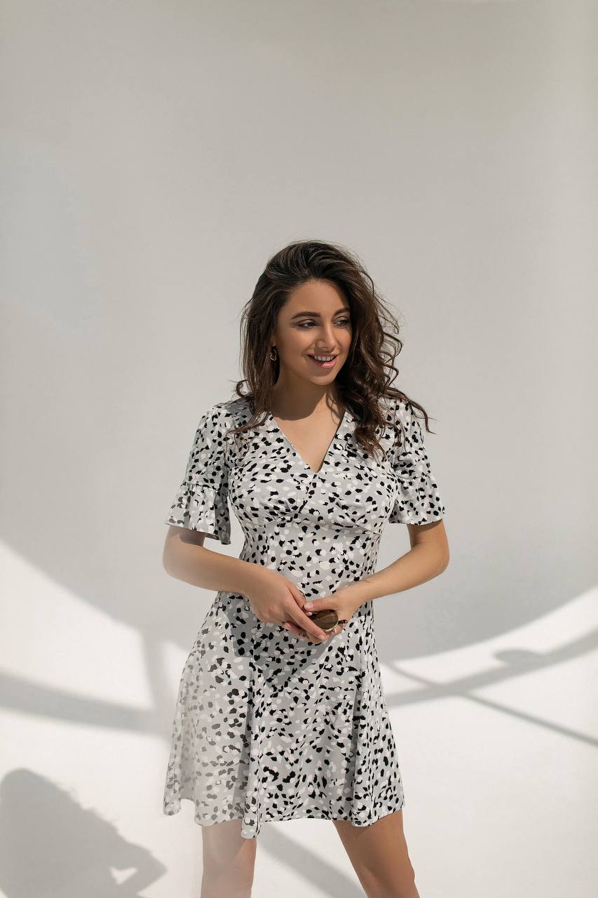 Woman wearing a black and white patterned dress against a plain background