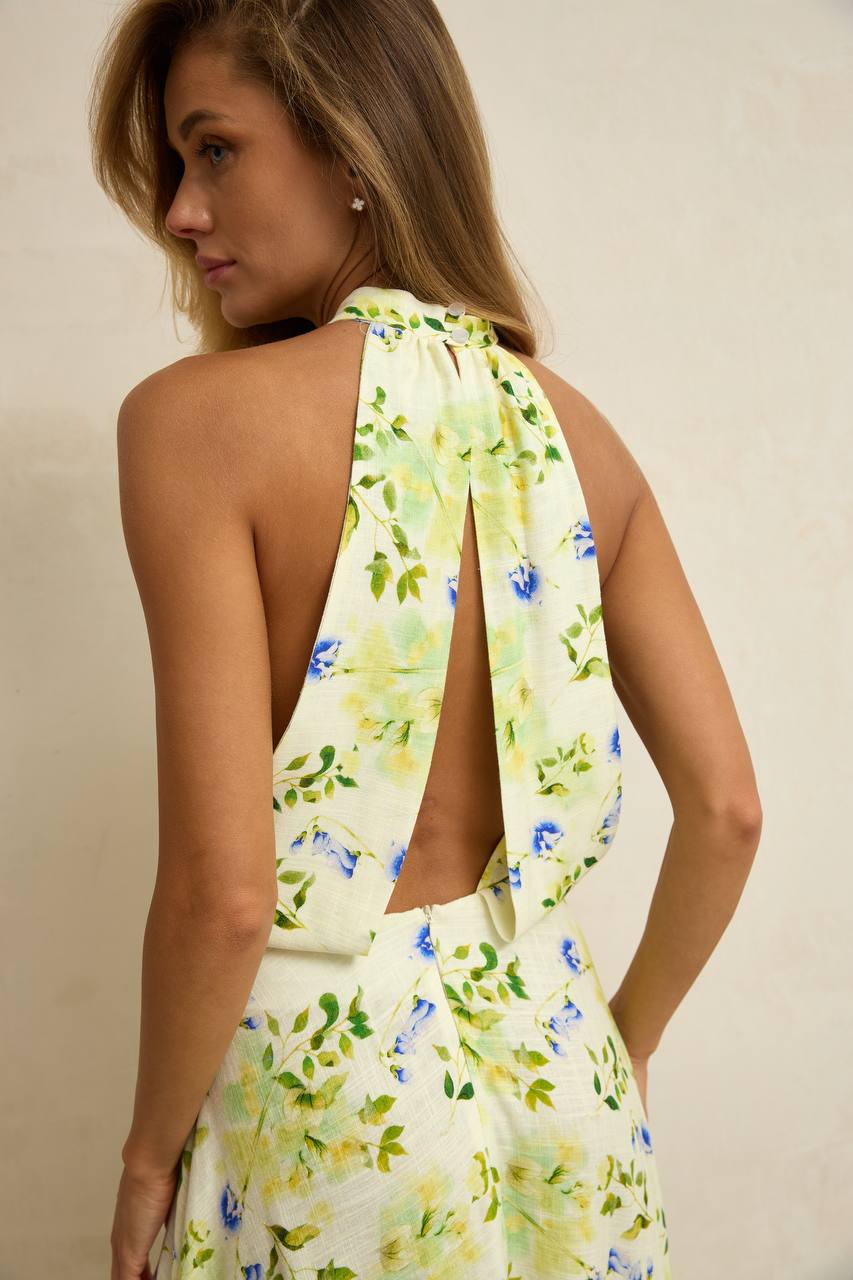 Woman wearing a floral dress with a halter neck design on a plain background