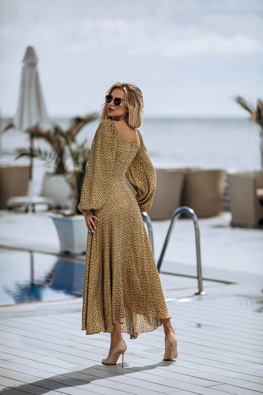 Woman in a patterned dress standing by a pool with ocean view