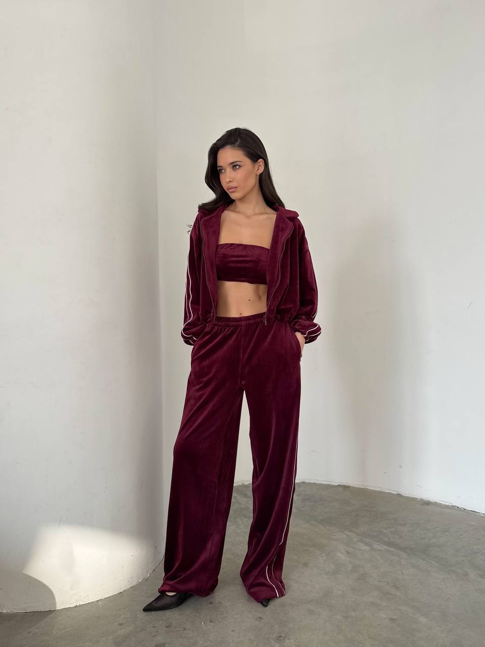 Woman wearing a burgundy velvet outfit against a plain background
