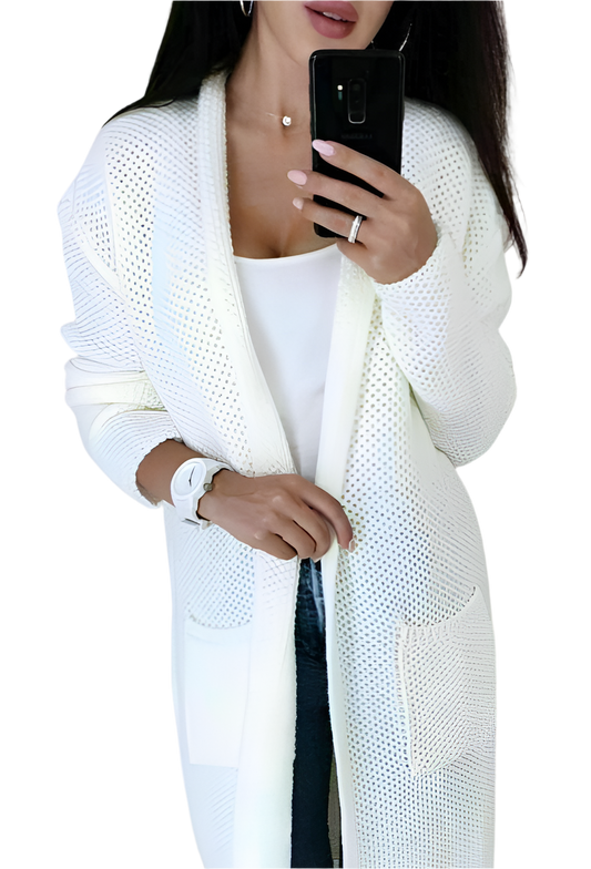 Woman wearing a white knit cardigan over a white top, holding a phone.