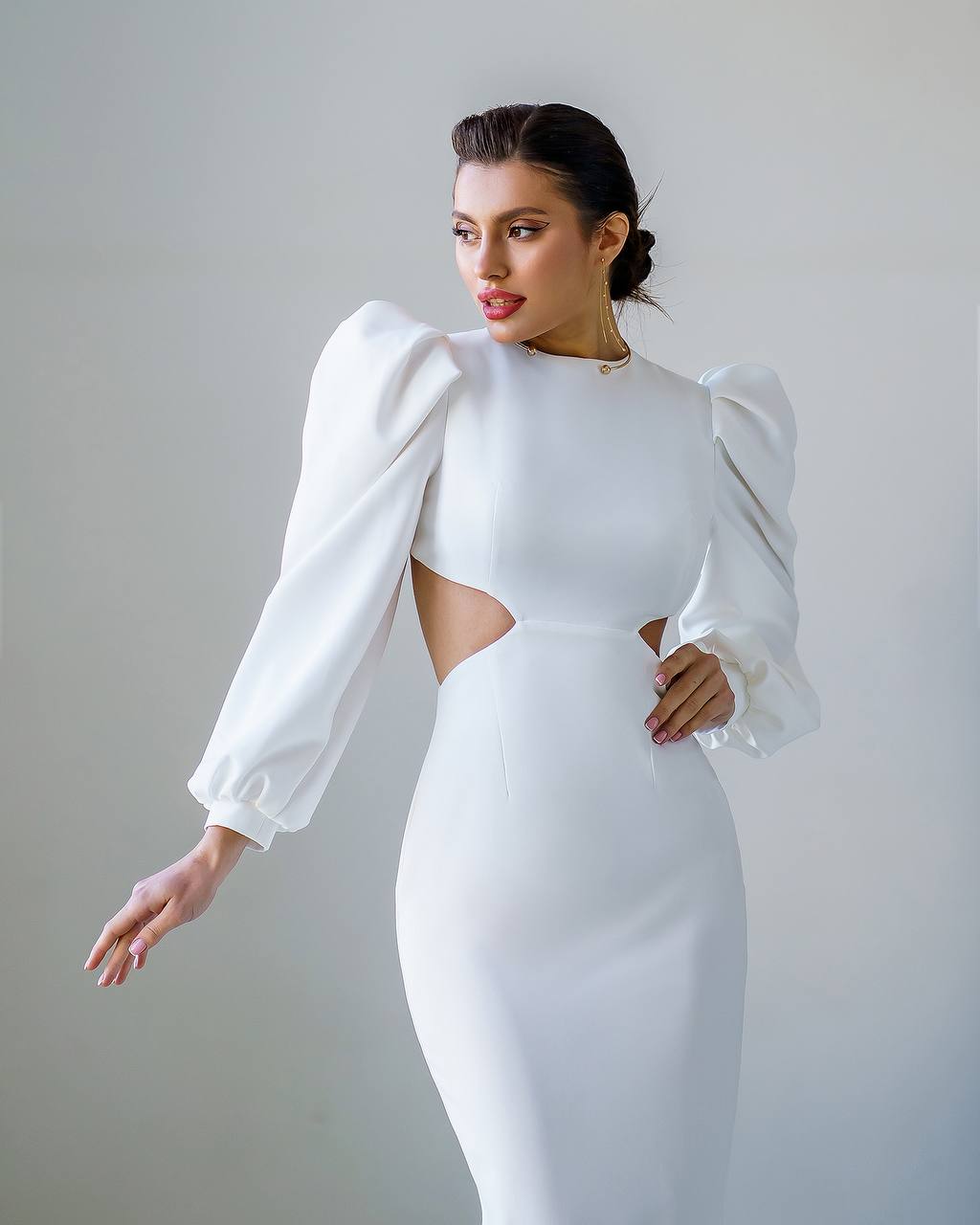 Woman wearing a white dress with puffed sleeves against a plain background