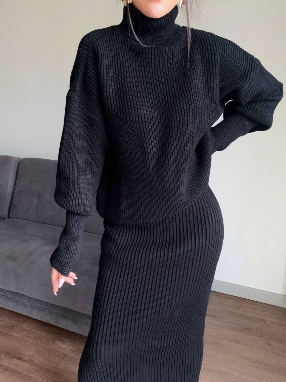 Person wearing a black ribbed knit set in a room with a gray couch.
