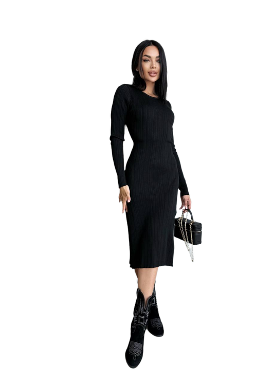 Woman wearing a black dress and black boots holding a black handbag on a white background