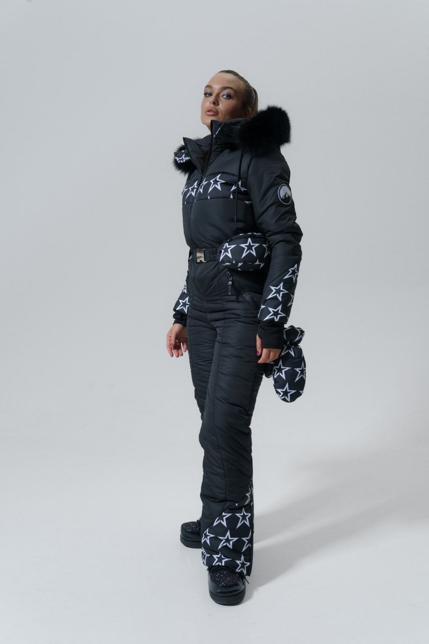 Person wearing a black snowsuit with star patterns on a white background