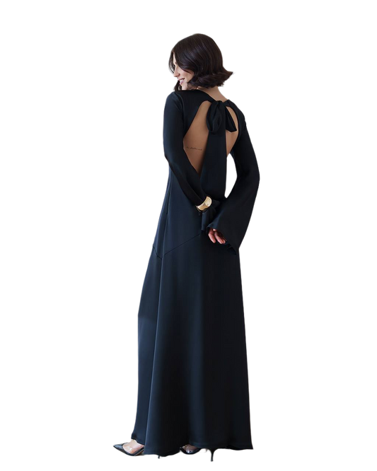 Woman wearing a long black dress with open back on a white background