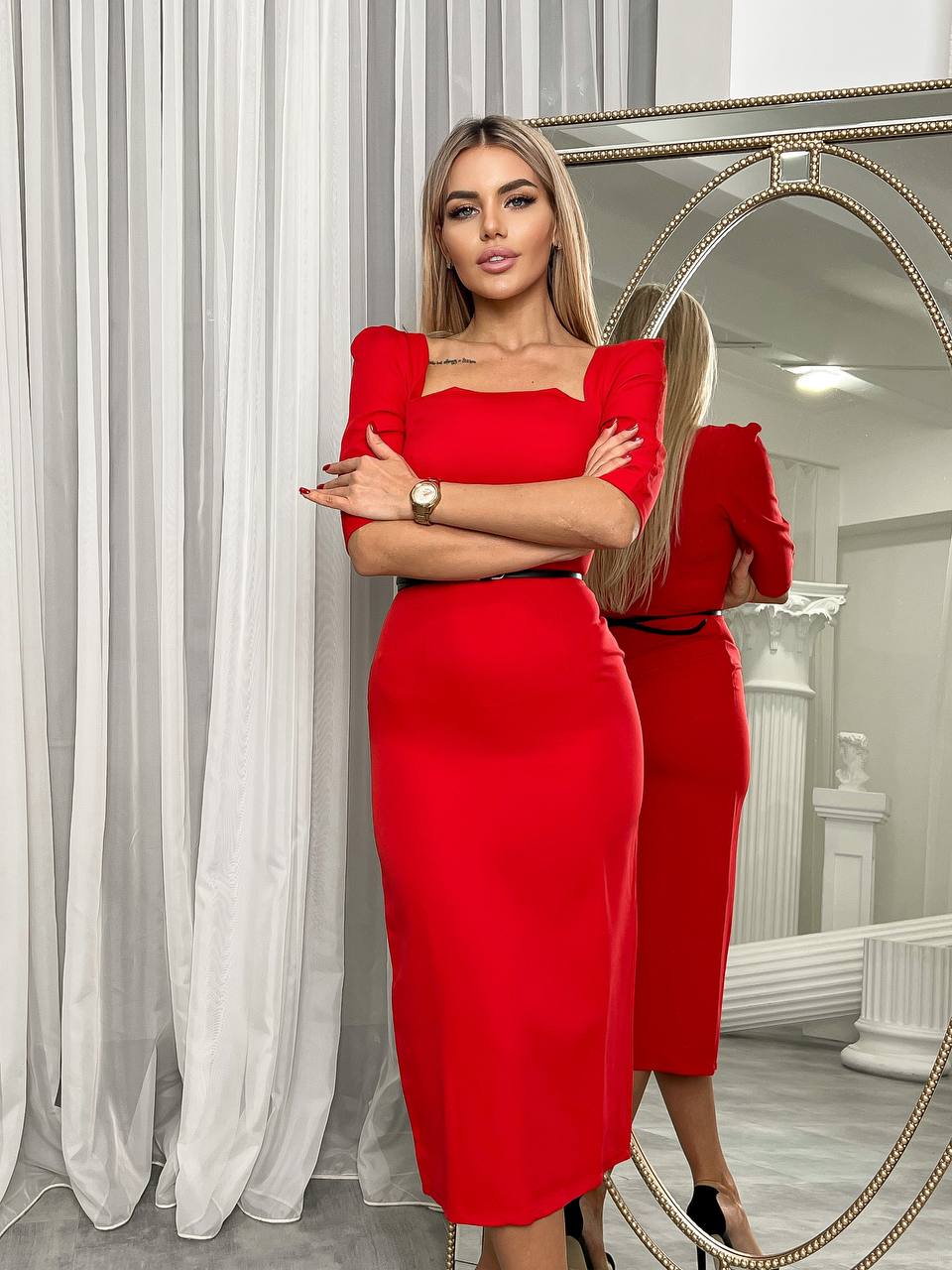 Woman in a red dress standing in front of a mirror.