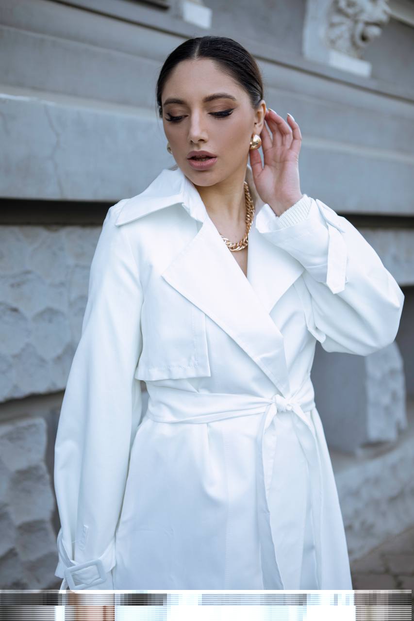 Woman wearing a white coat in front of a marble wall