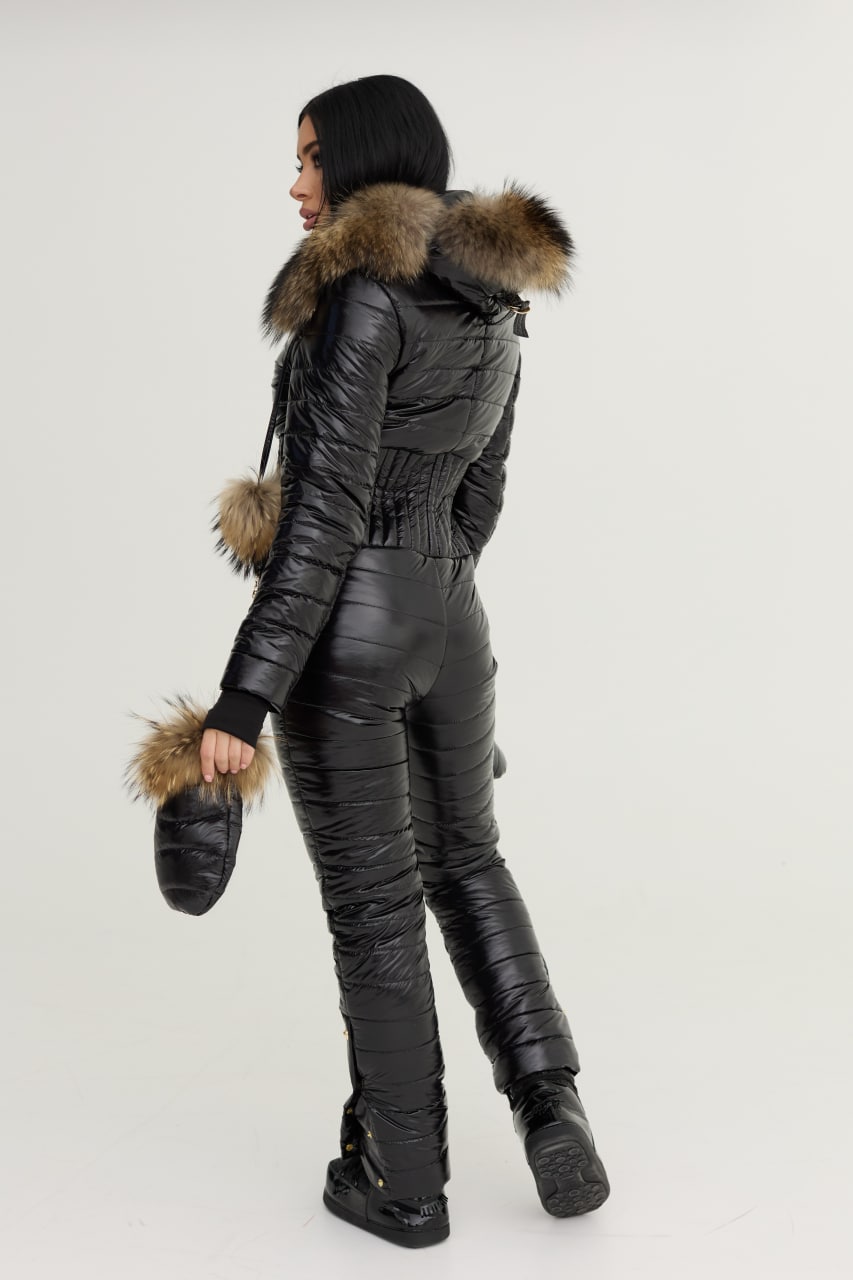 Person wearing a black quilted jumpsuit with fur trim on a white background