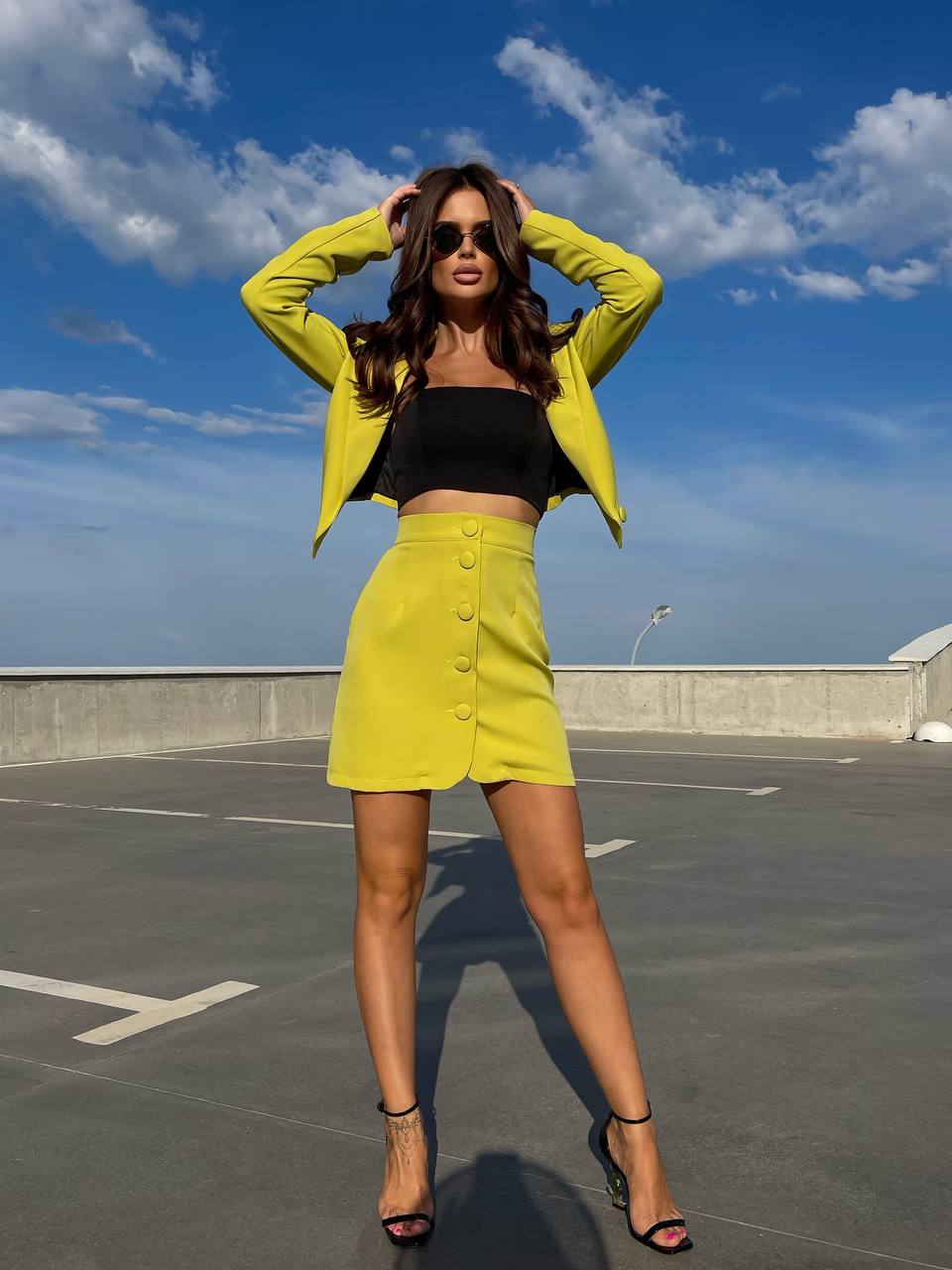Woman in a yellow outfit standing on a rooftop with a blue sky background