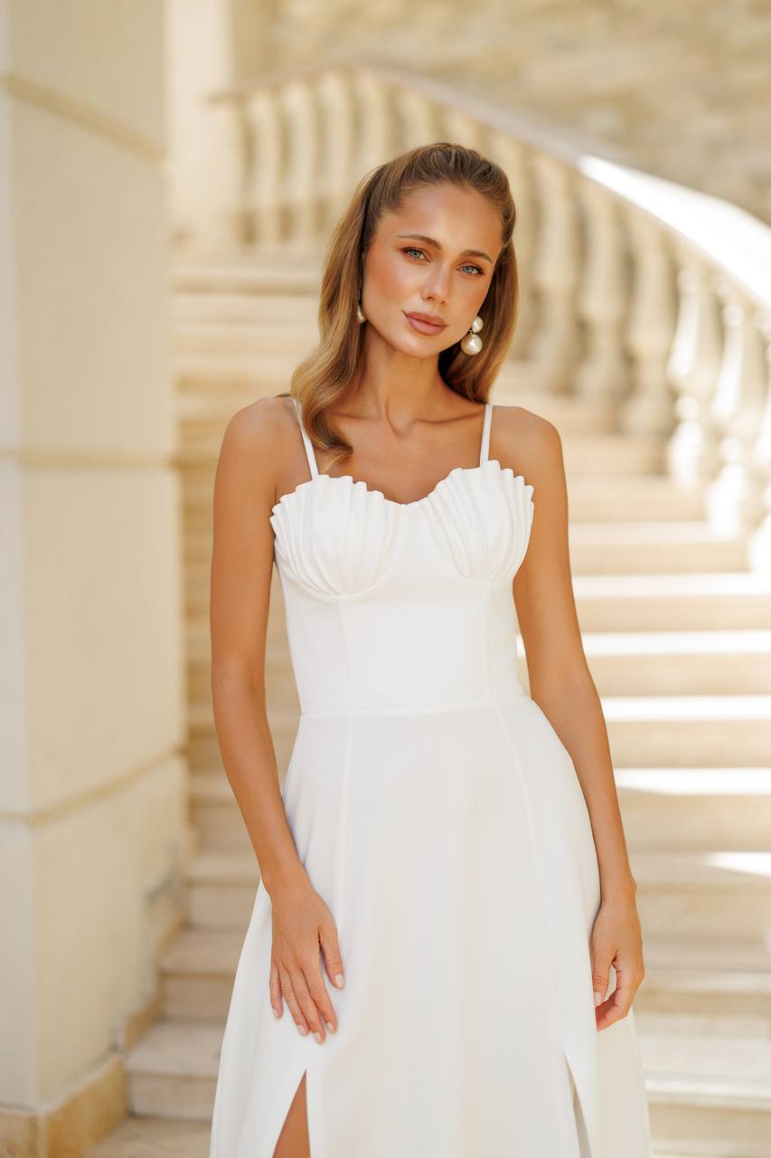 Woman wearing a white dress standing outdoors with steps in the background