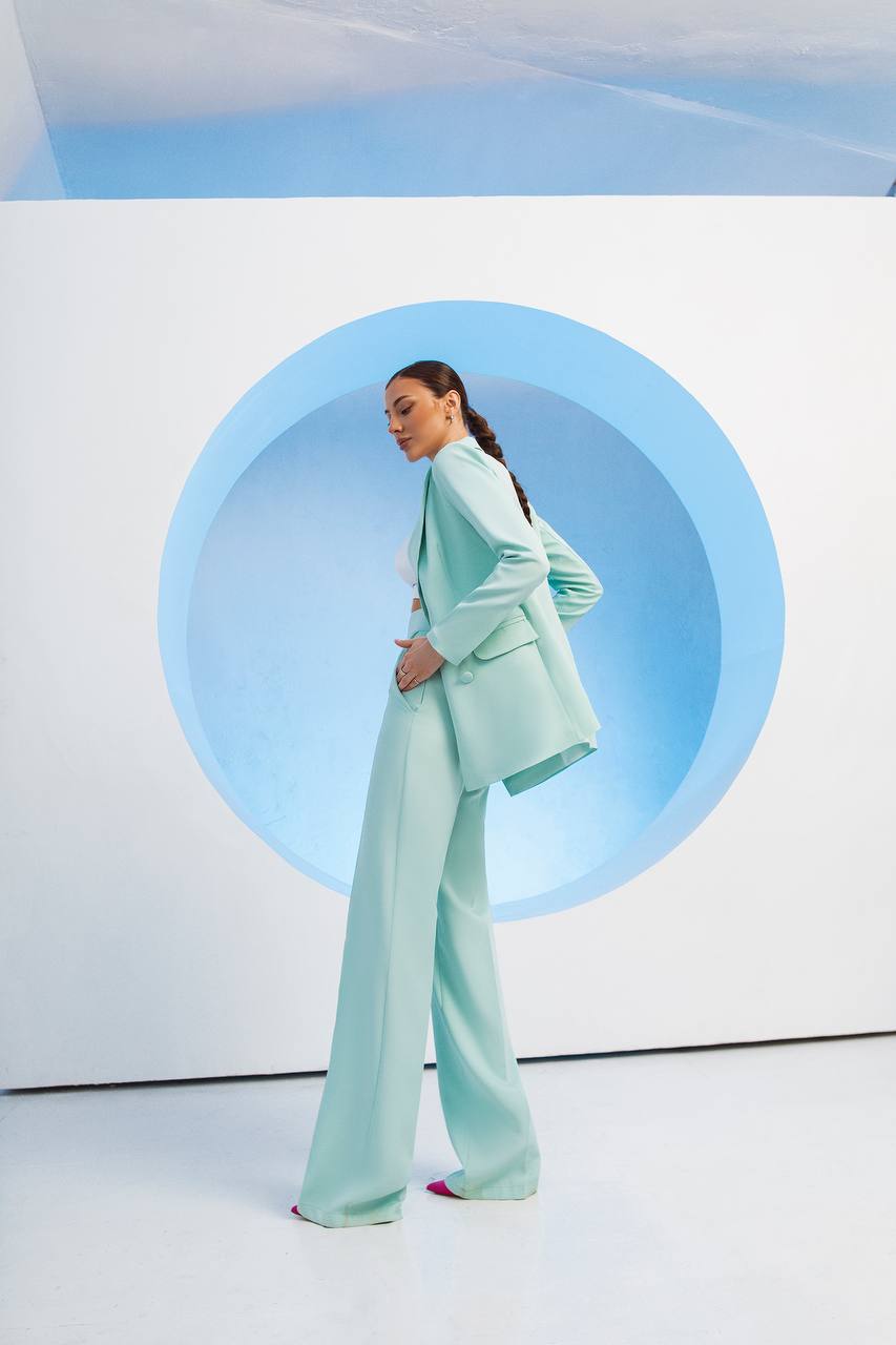 Person wearing a light blue suit standing in front of a circular blue light on a white background
