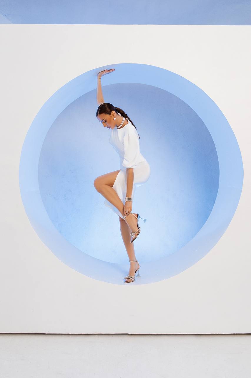 Woman in a white outfit standing inside a large blue circle on a white background
