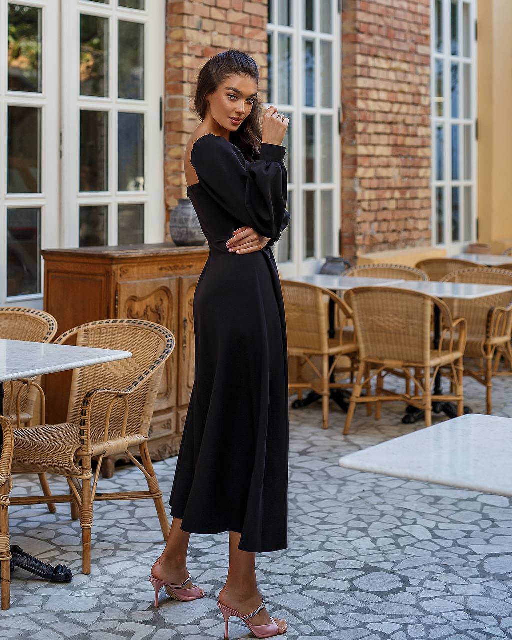 Woman in a black dress standing in an outdoor cafe setting