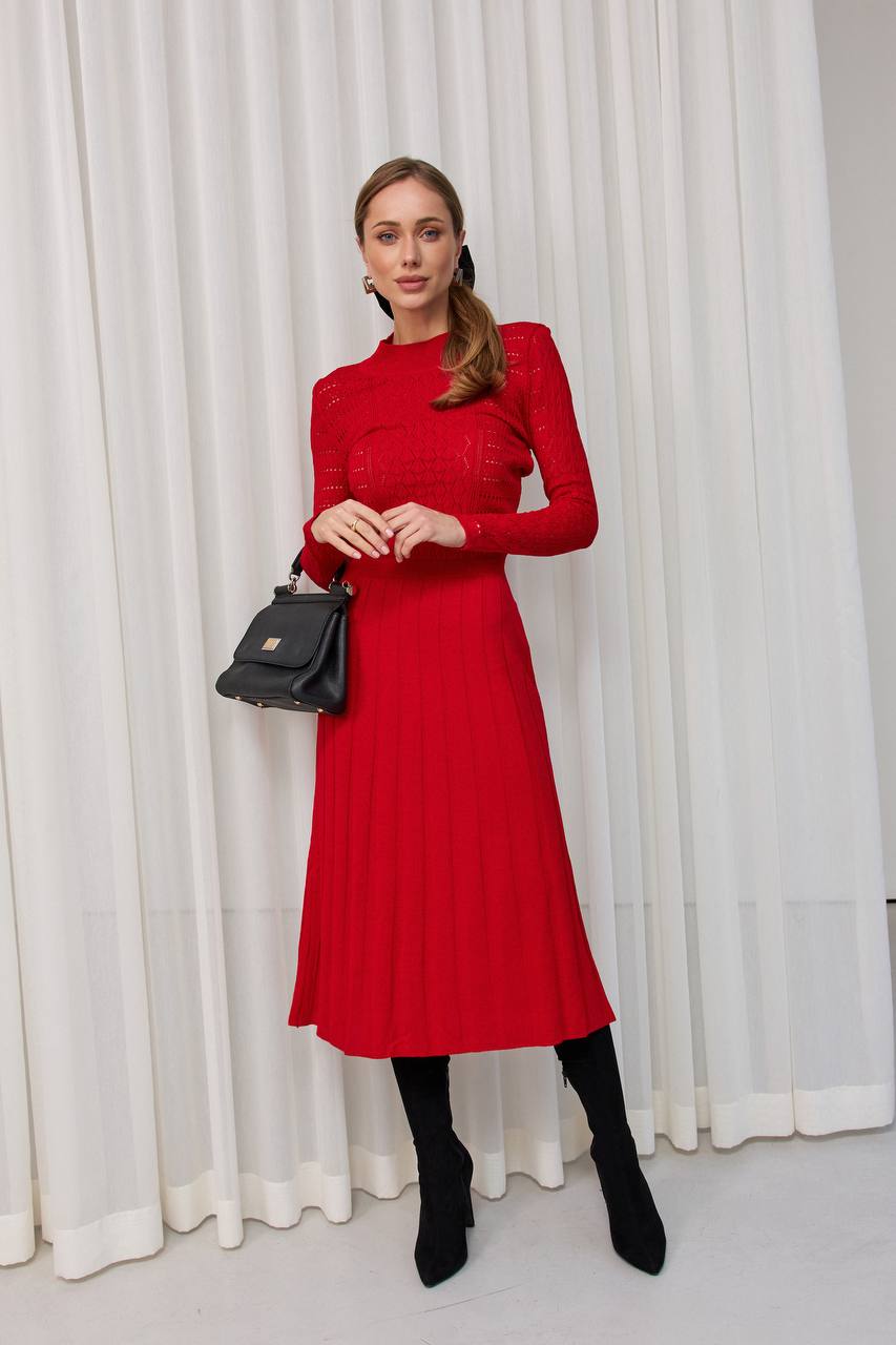 Woman wearing a red dress with a black handbag against a white curtain background