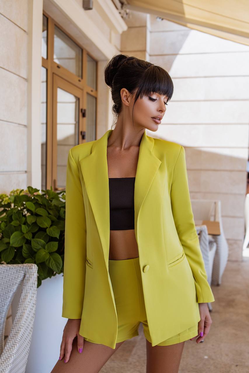 Woman wearing a bright yellow outfit standing outdoors.