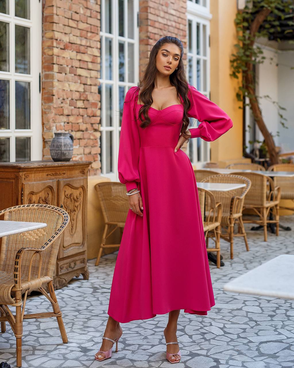Woman in a pink dress standing in an outdoor cafe setting