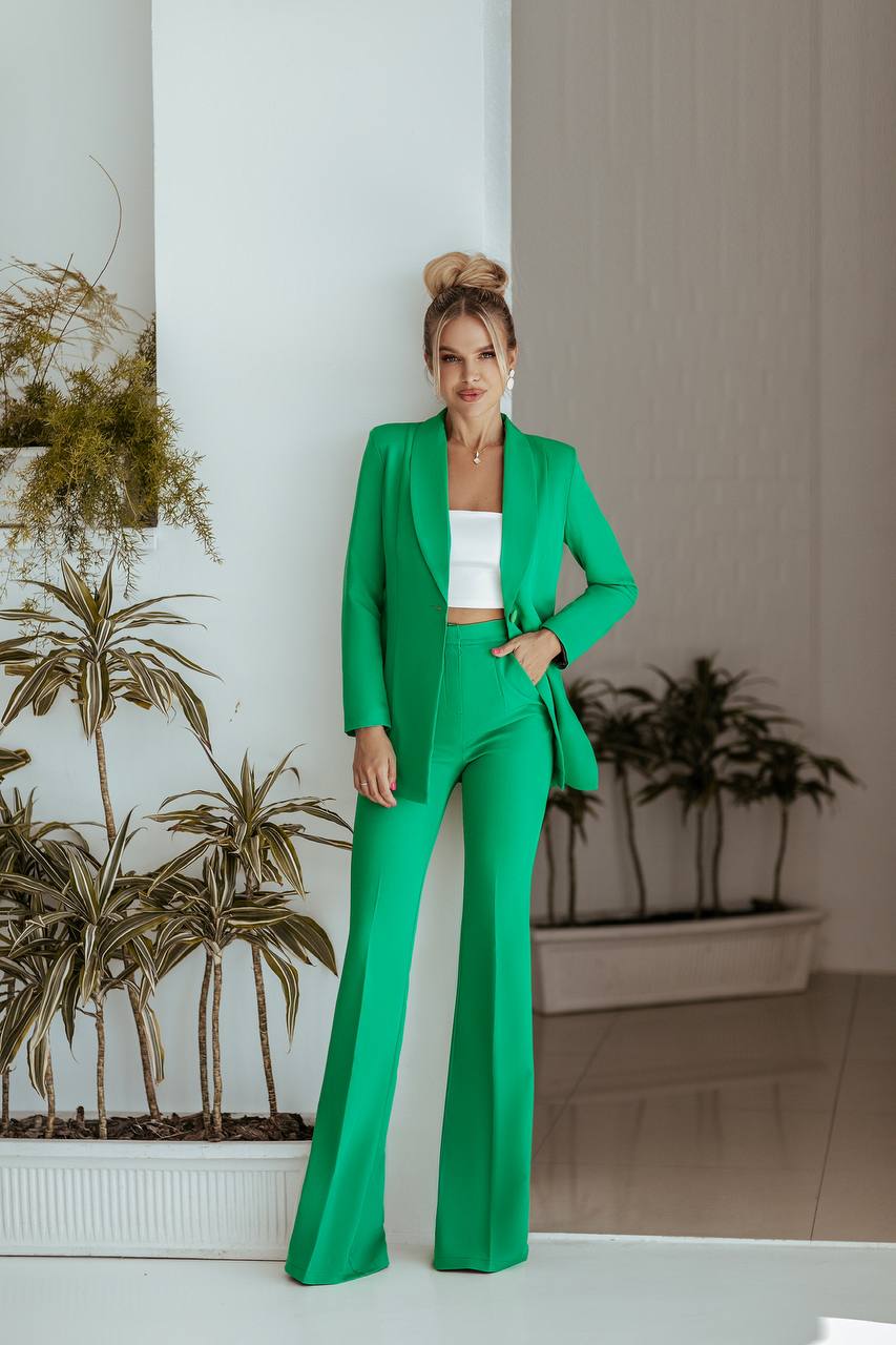 Woman in a green suit standing indoors with plants in the background