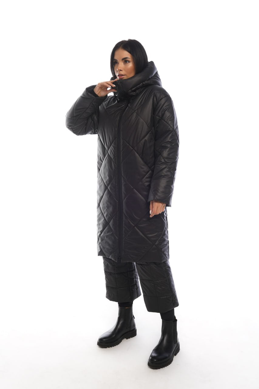 Person wearing a black quilted coat on a white background