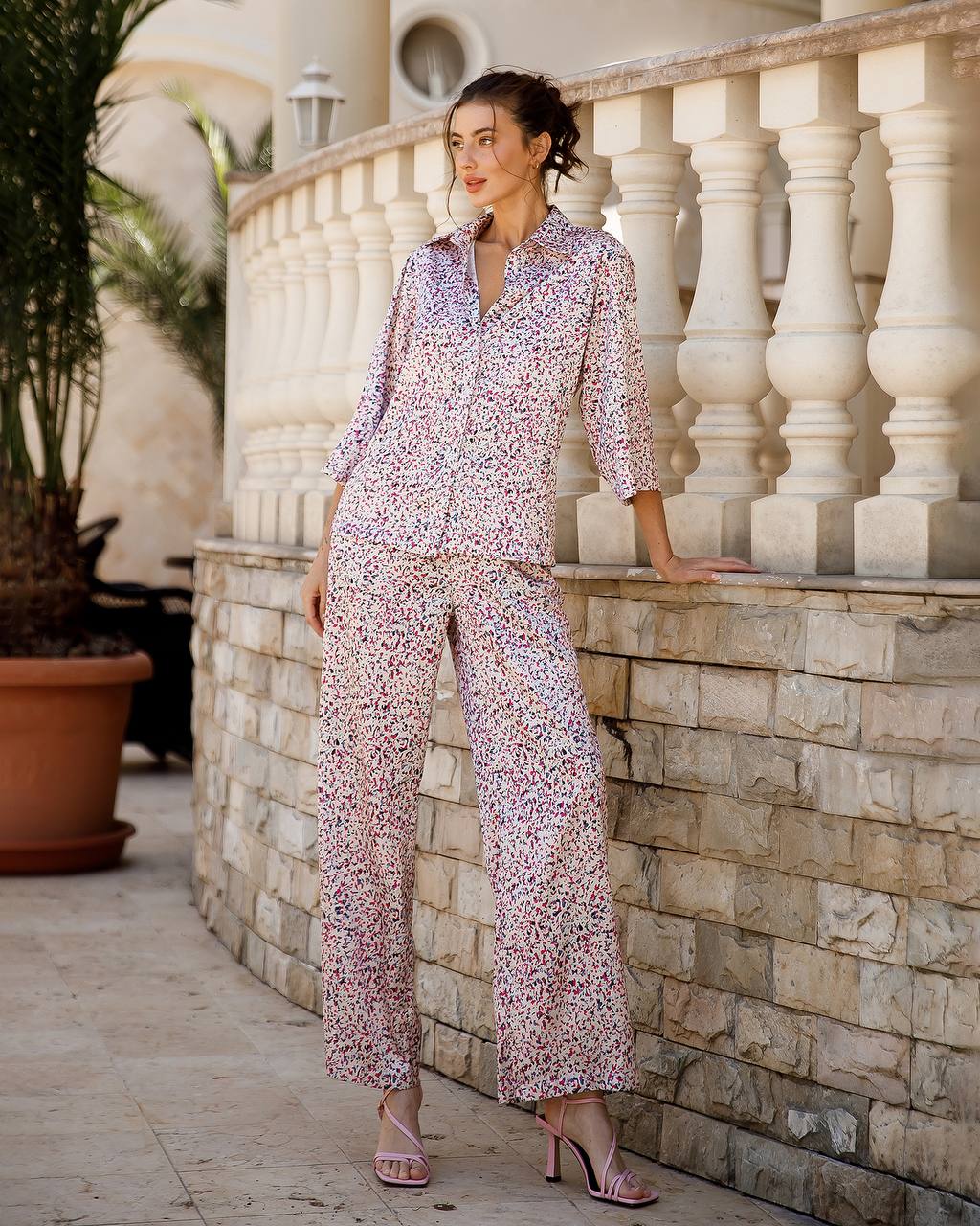 Woman in a floral outfit standing on a stone patio with decorative columns.