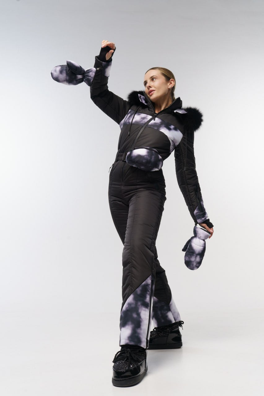 Person wearing a black and gray outfit with fur-lined hood on a white background