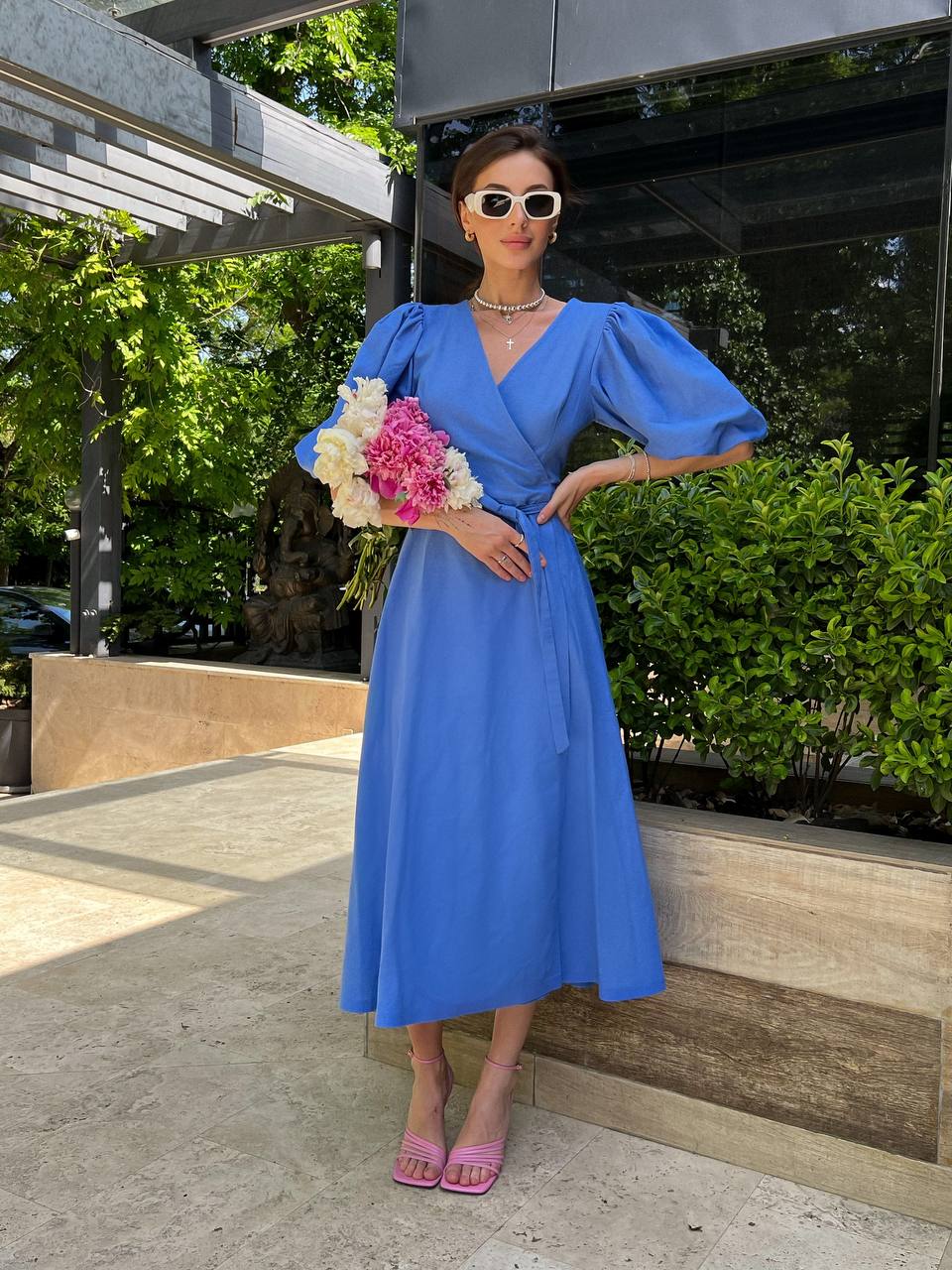 Woman in a blue dress holding flowers outdoors