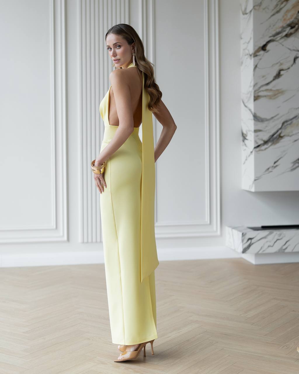 Woman in a yellow dress standing in a room with marble accents