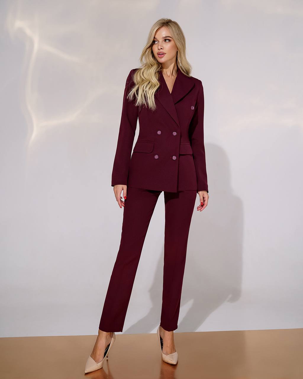 Woman wearing a burgundy suit against a white background