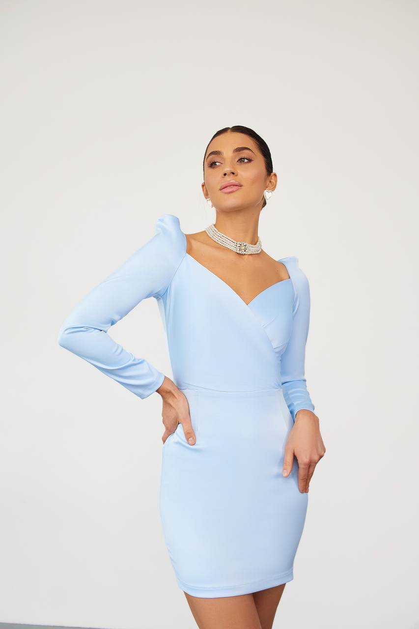 Woman wearing a light blue dress with long sleeves on a white background