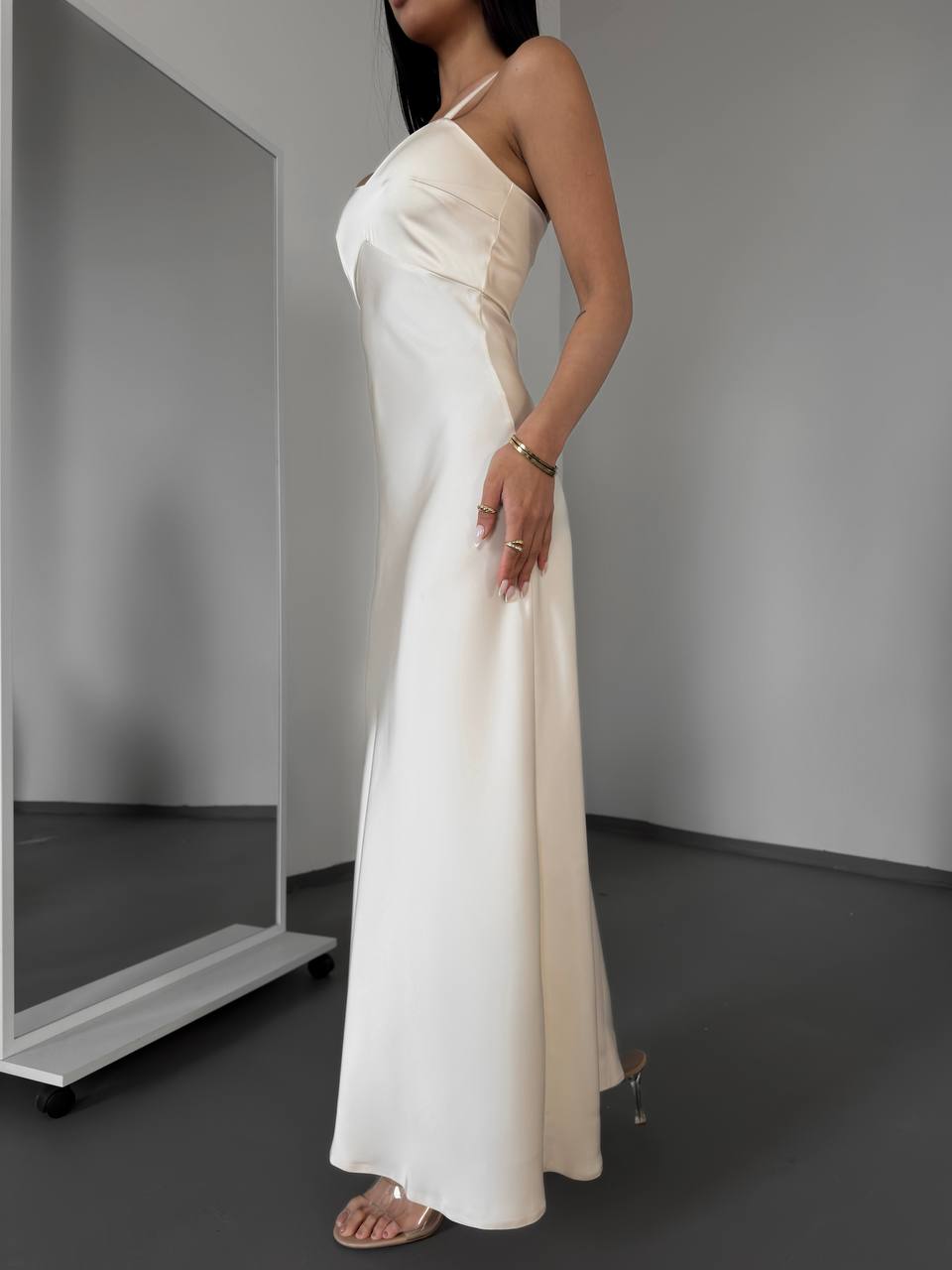 Woman wearing a white one-shoulder dress in a minimalistic setting