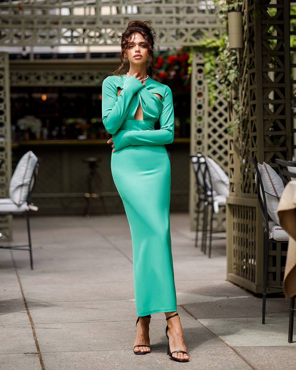 Woman in a teal outfit standing outdoors with a blurred background