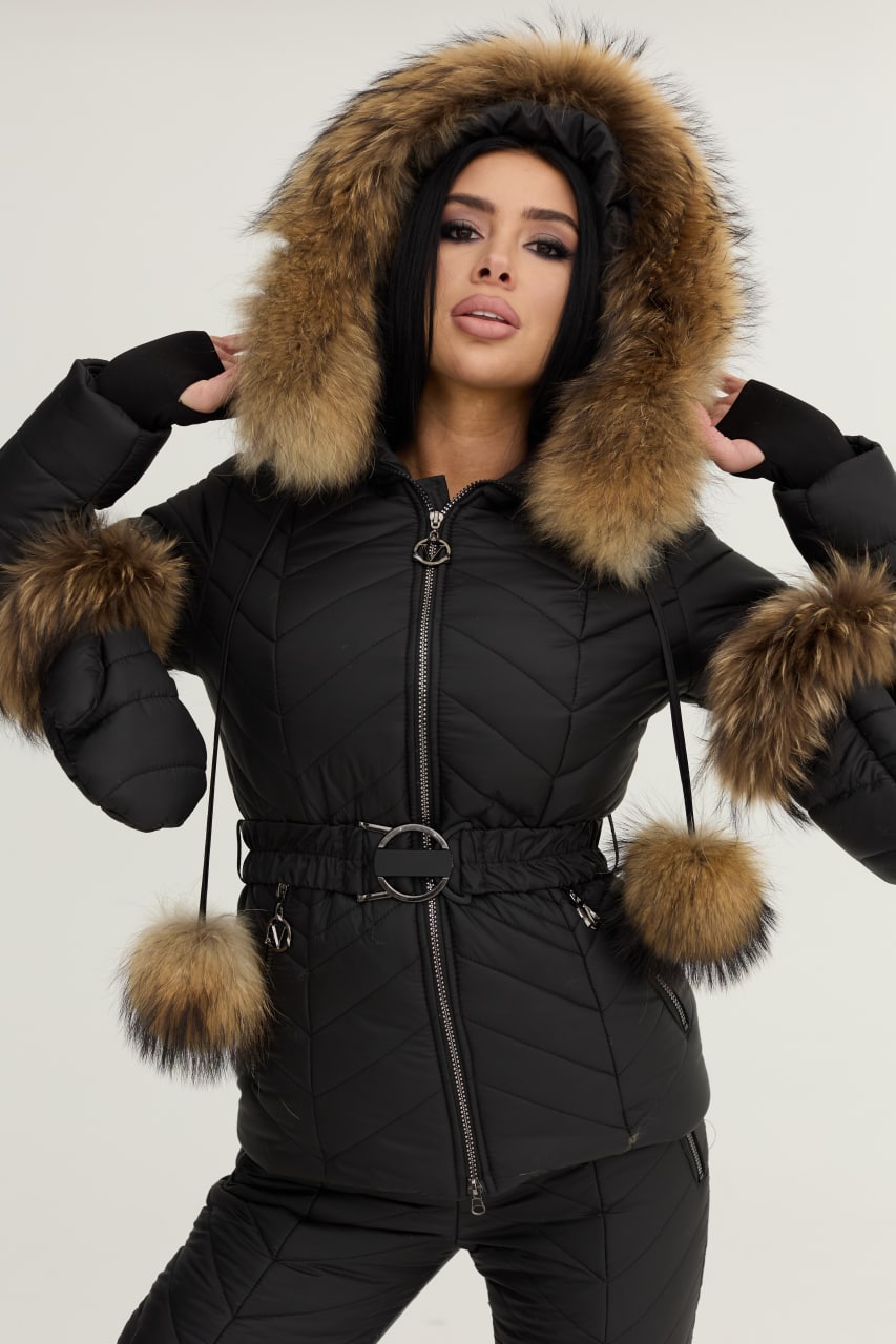 Person wearing a black quilted jacket with fur-lined hood and cuffs on a white background