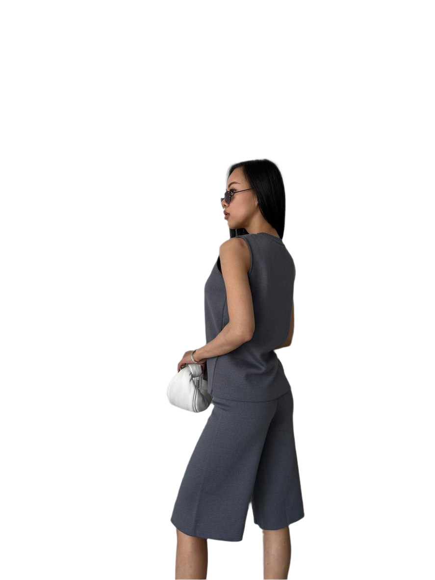 Woman wearing a gray sleeveless top and skirt set on a white background