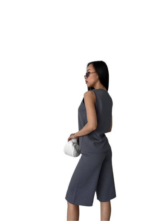 Woman wearing a gray sleeveless top and skirt set on a white background