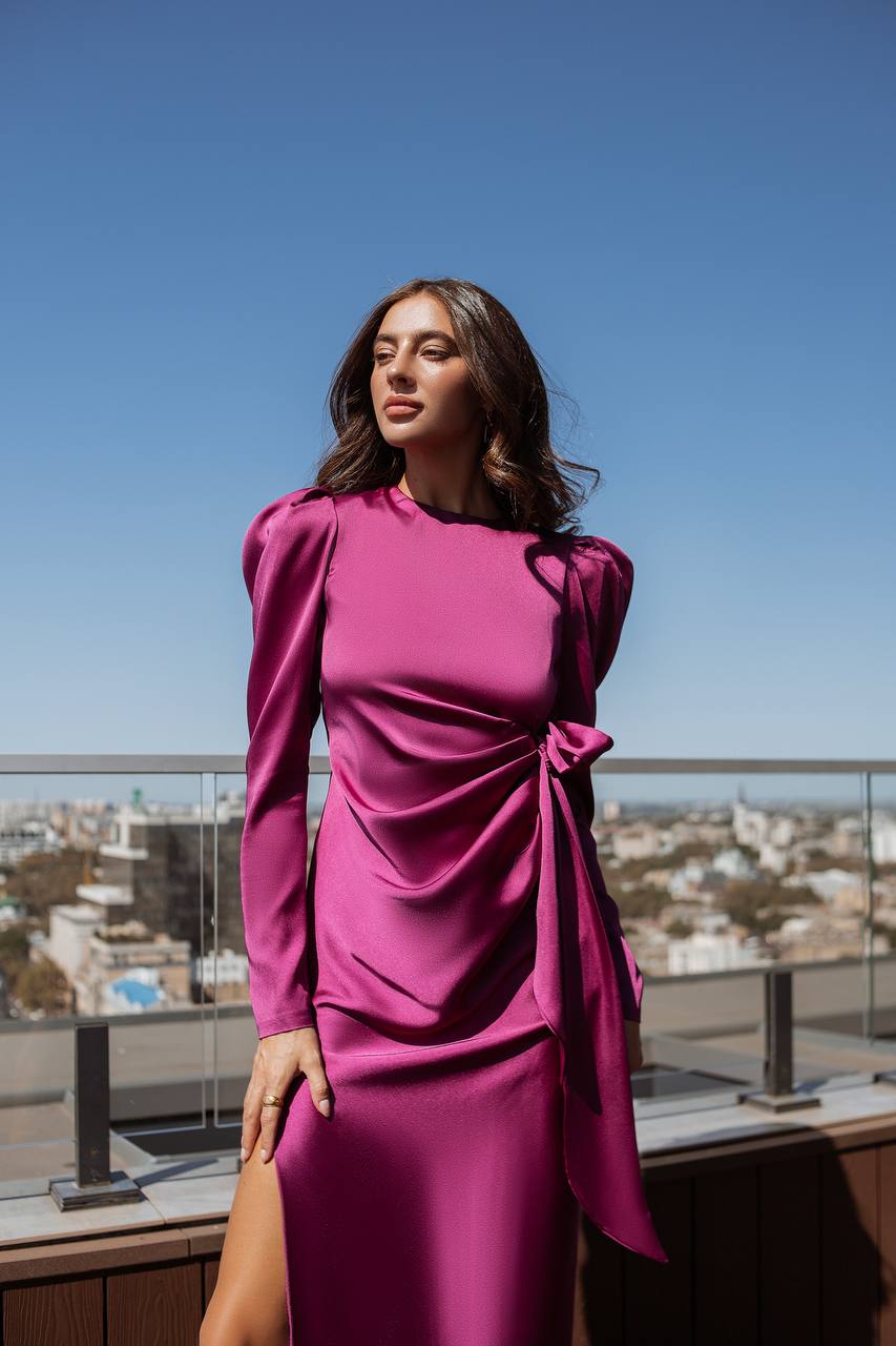 Woman in a pink dress standing on a rooftop with a clear blue sky