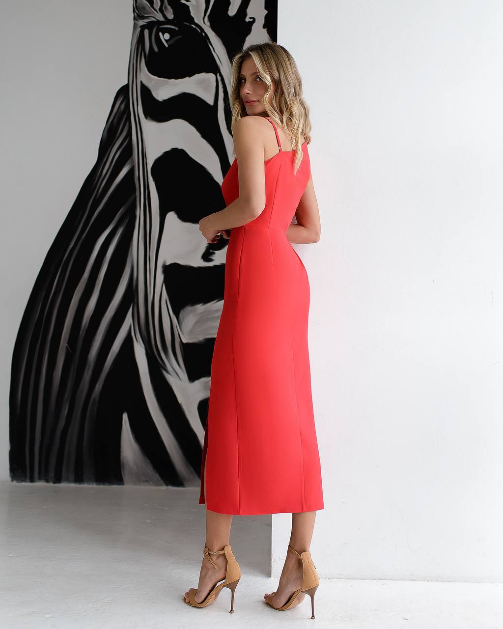 Woman in a red dress standing in front of a zebra painting