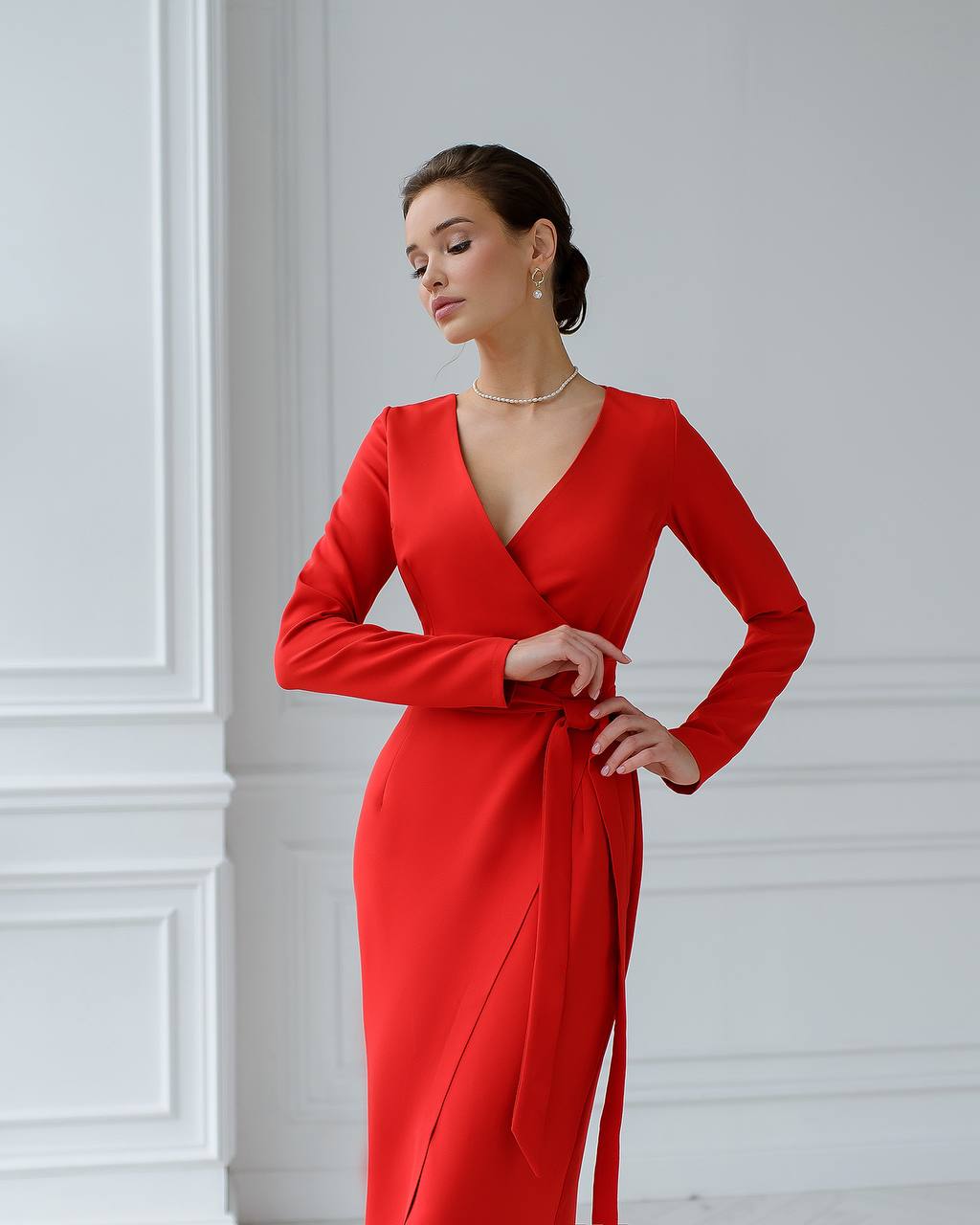 Woman wearing a red dress against a white wall