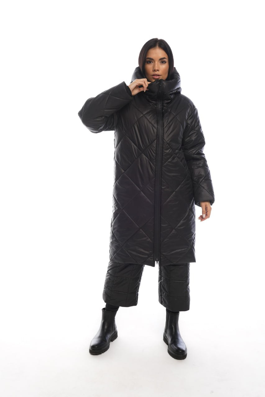 Person wearing a long black quilted coat on a white background