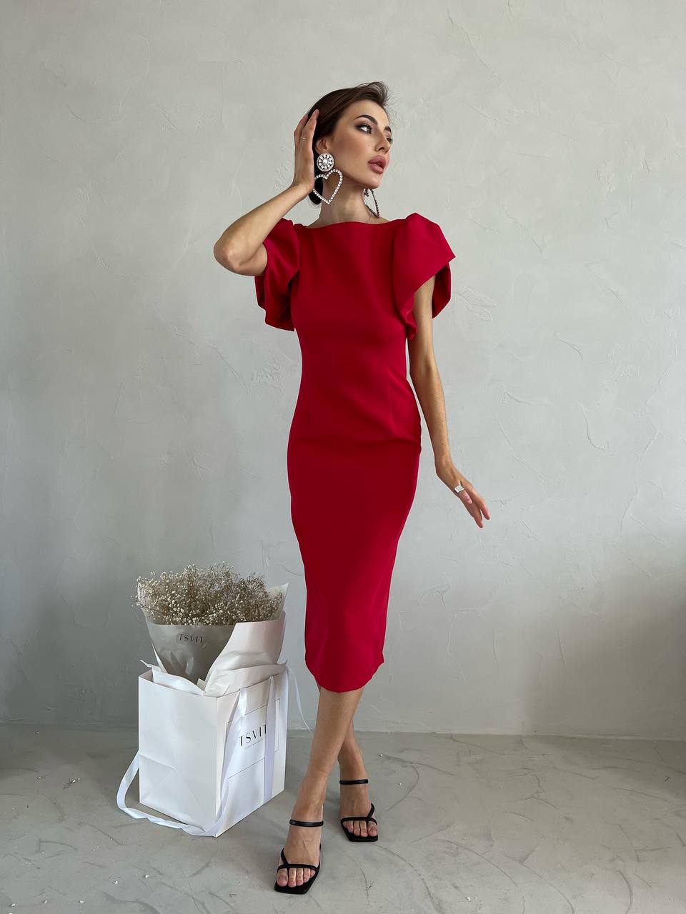 Woman wearing a red dress with ruffled sleeves against a plain background