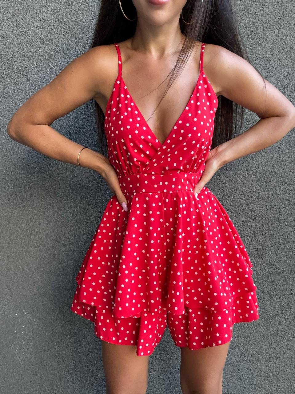 Woman wearing a red polka dot dress against a gray background