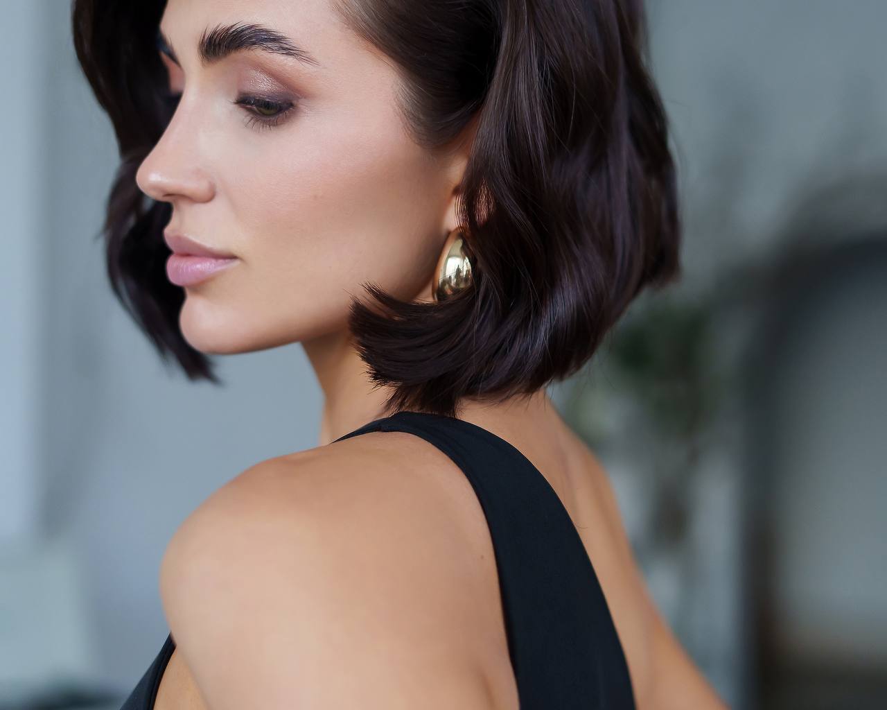 Woman with styled hair and earrings against a blurred background