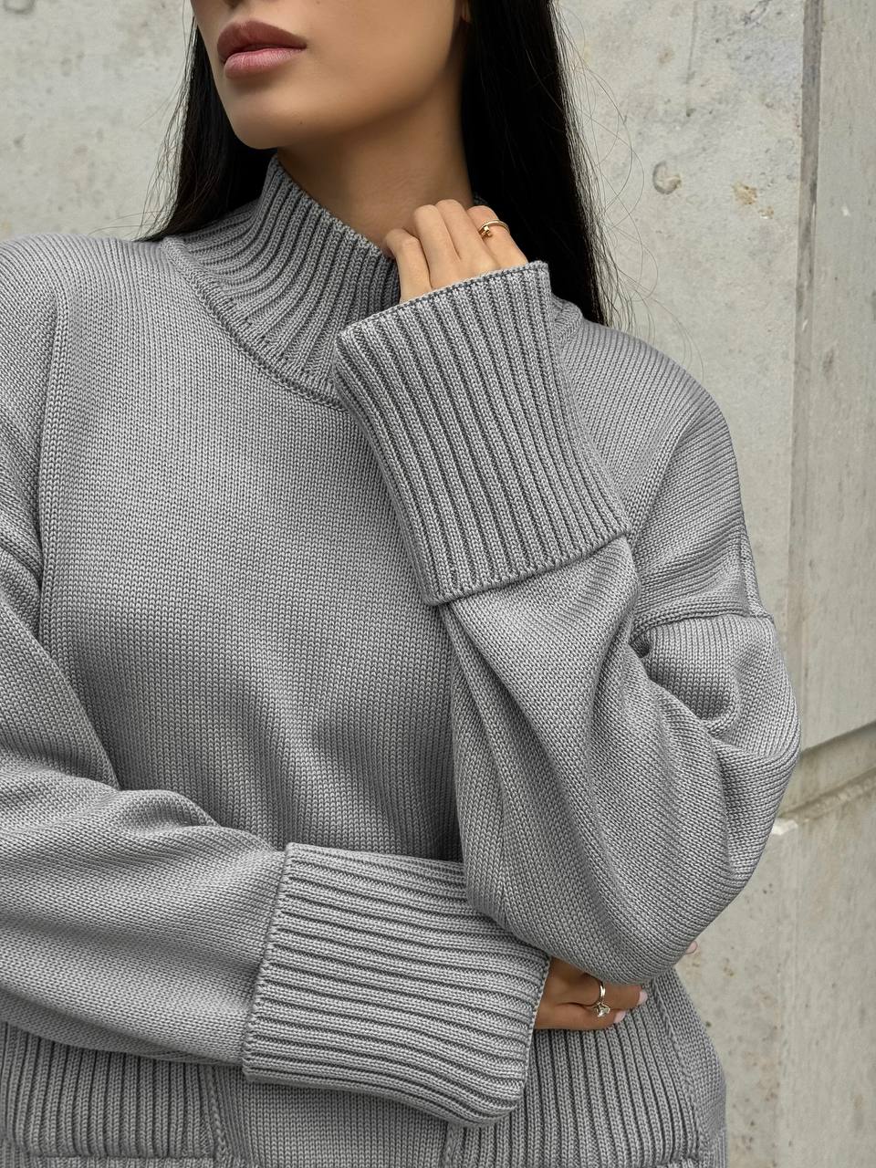 Gray ribbed sweater worn by a person against a neutral background