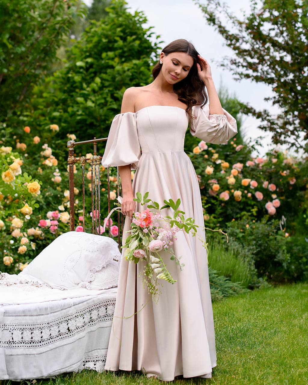 Woman in a white dress holding flowers in a garden setting