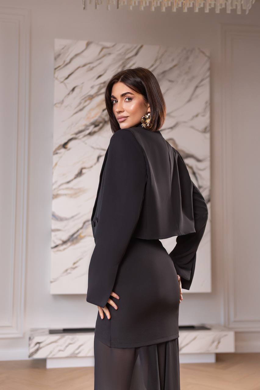 Woman in a black outfit standing in a room with a textured wall painting.